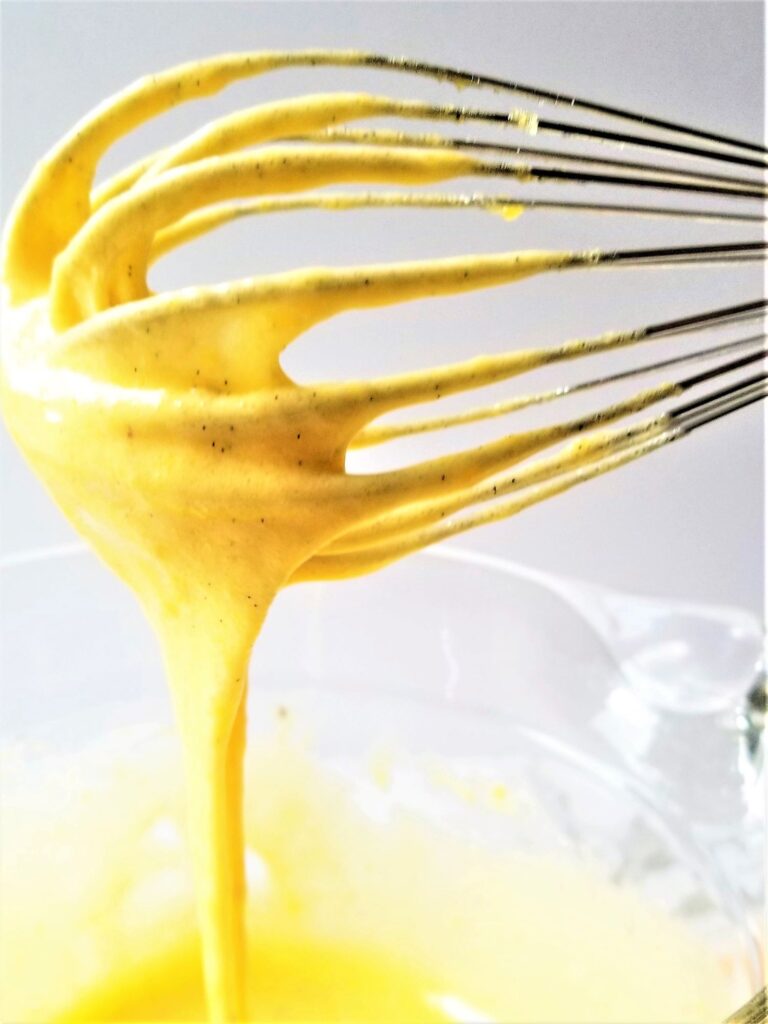 thickened egg yolks and sugar mixture falling from tines of whisk