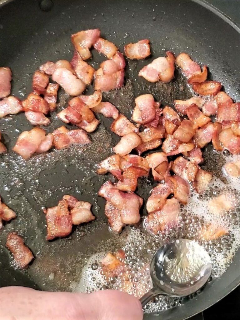 frying bacon pieces and skimming extra bacon grease from top