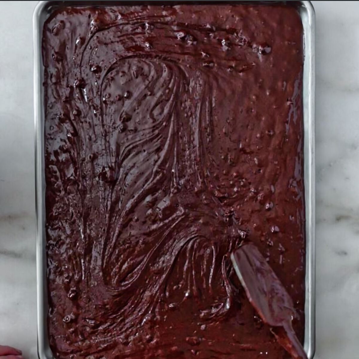 spreading brownie batter in sheet pan.