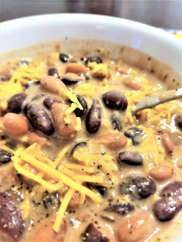 bowl of mexican bean soup with cheddar cheese sprinkled on top