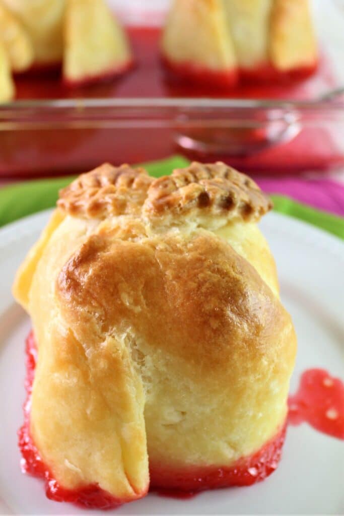 apple dumpling on white plate with red sauce underneath