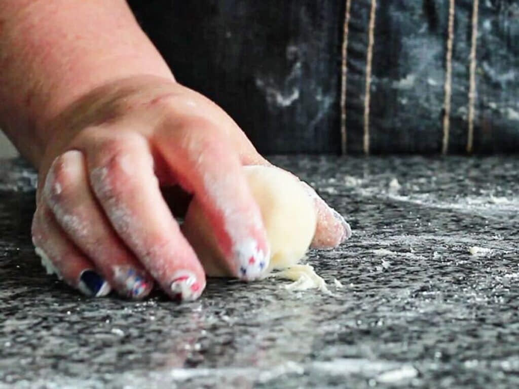 rolling dough using cupped hand to create a tight ball.