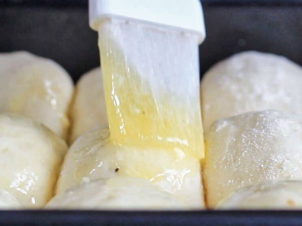 brushing risen unbaked rolls with melted butter.