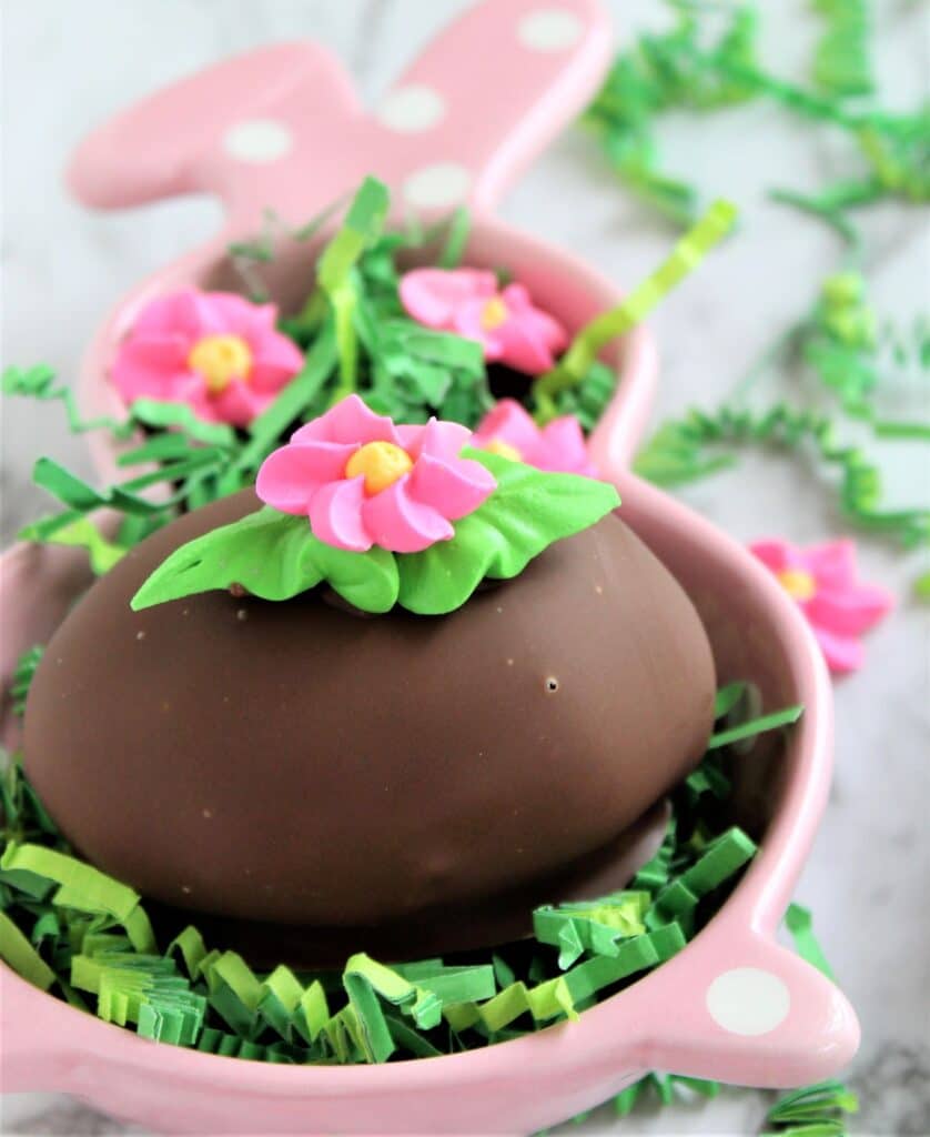 chocolate easter egg in pink bunny dish with green easter grass