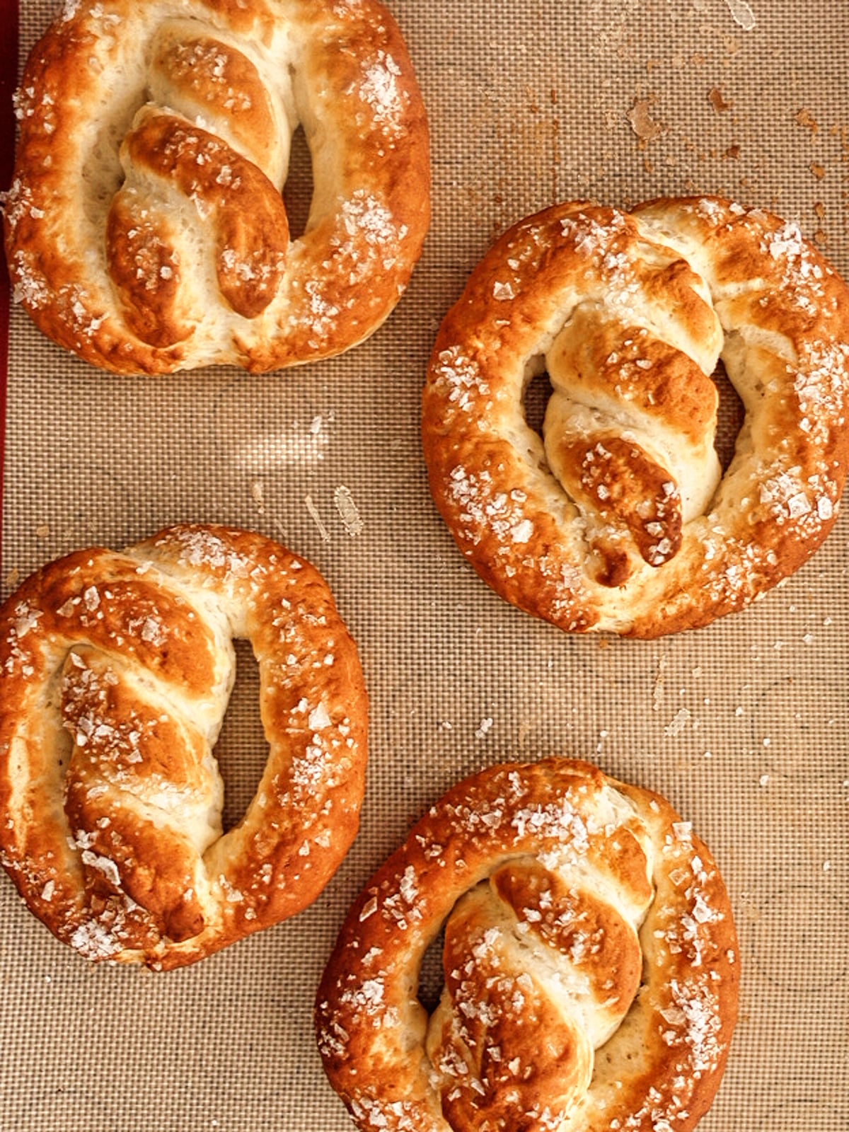 four pretzels on silicone baking mat.