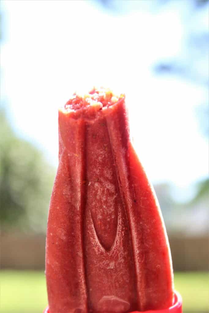 strawberry balsamic popsicle with a bite out of it