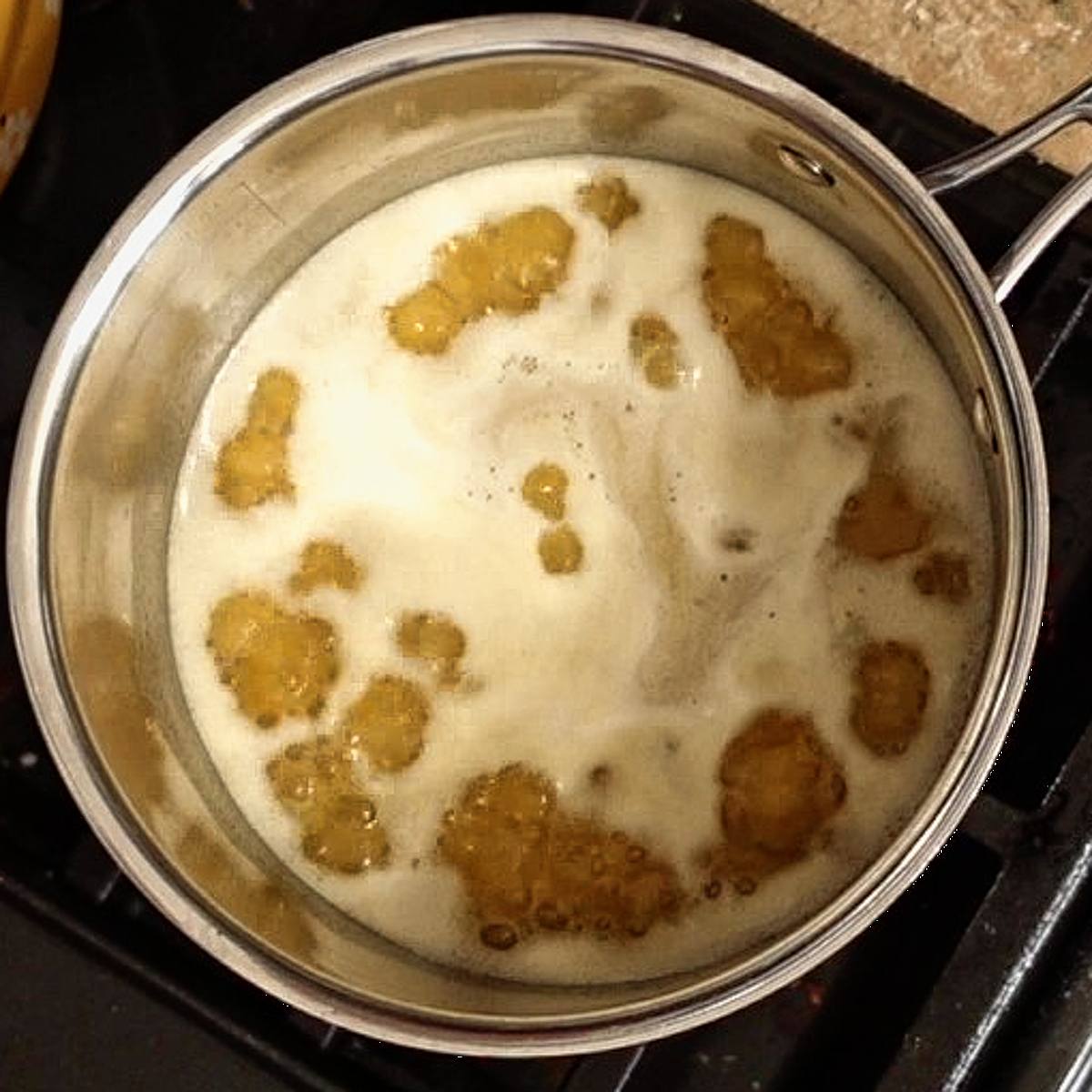 simmering orange juice with sugar and mustard on stovetop.