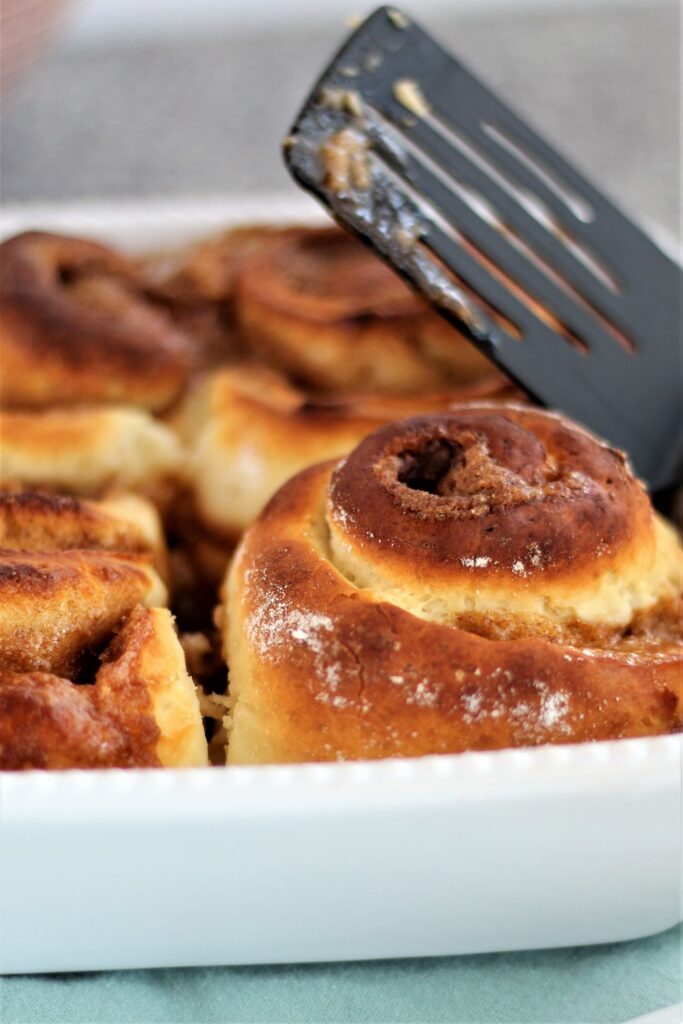 unfrosted baked cinnamon rolls in white baking pan