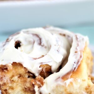 large cinnamon roll with icing on white plate