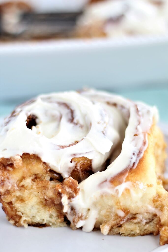 large cinnamon roll with icing on white plate