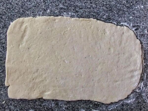 dough rolled out to large rectangle on granite countertop.
