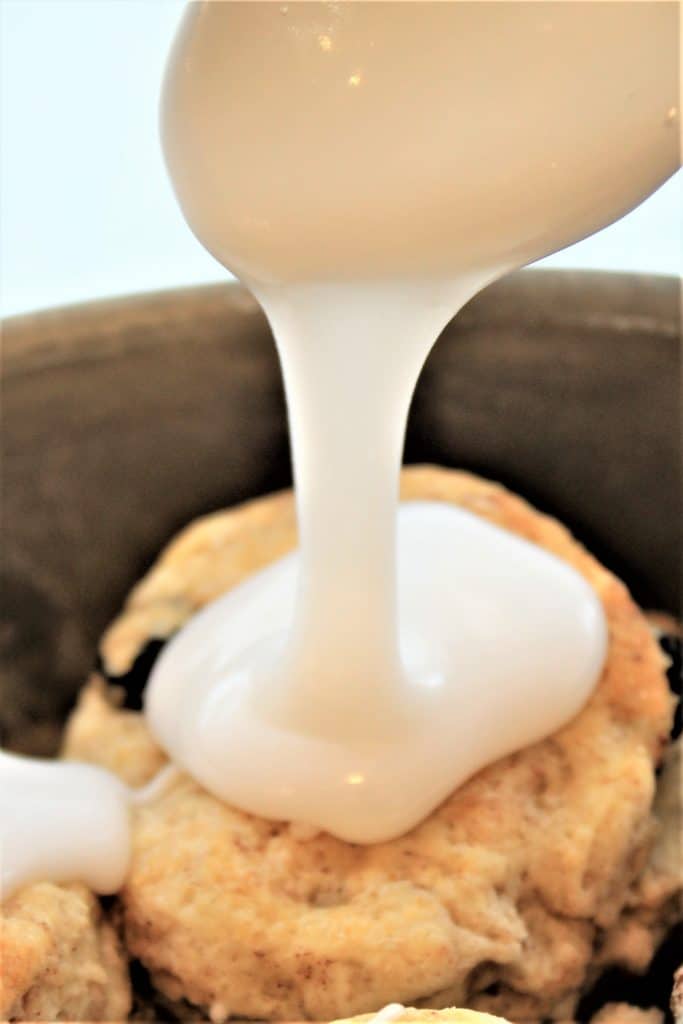pouring icing on cinnamon raisin biscuit