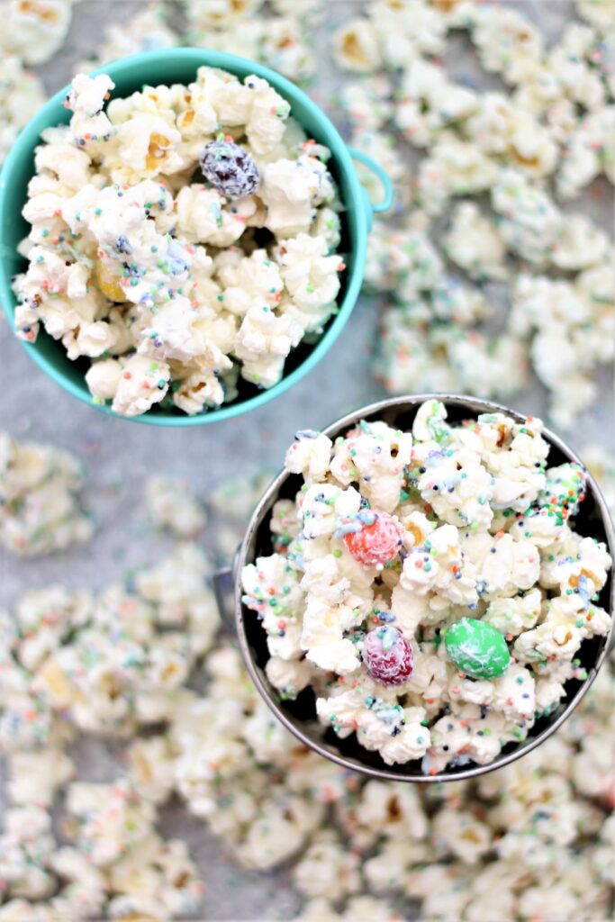 overhead shot of white chocolate popcorn in small pails with popcorn scattered about