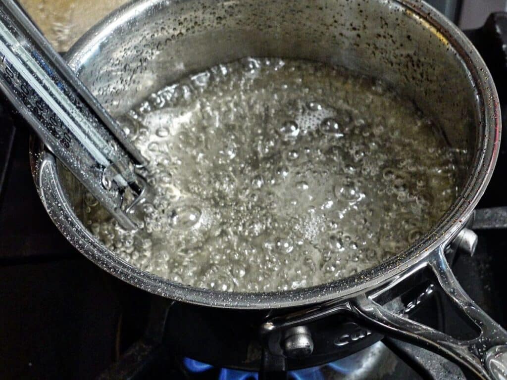 boiling sugar syrup in small saucepan with candy thermometer attached.