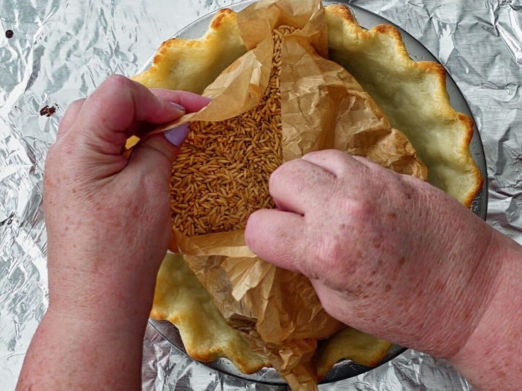 removing parchment and rice from inside of parbaked pie crust.