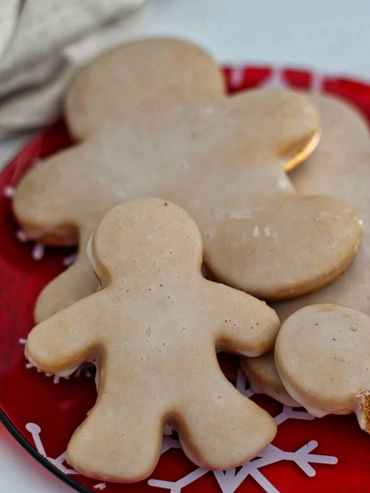 large and small glazed gingerbread men cookies on red glass plate.