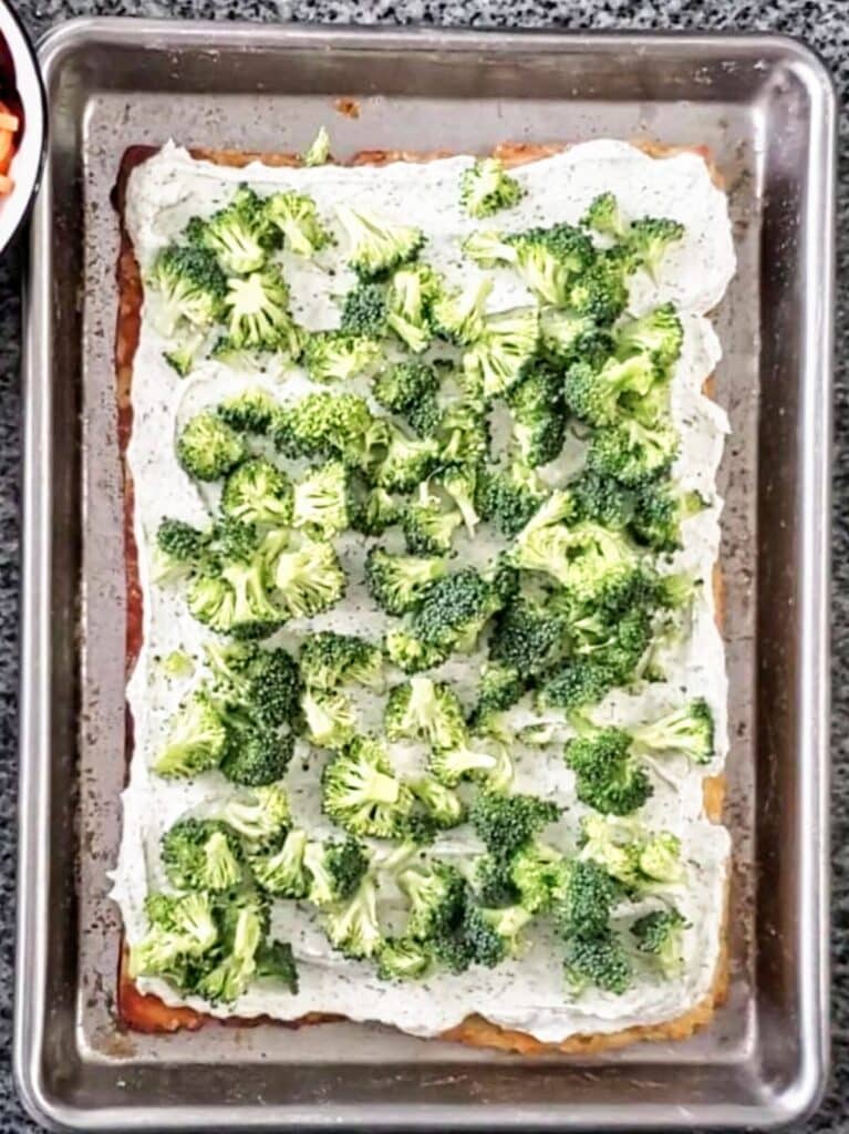 adding bite-sized broccoli florets on top of cream cheese.