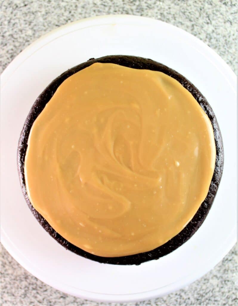 spreading caramel on top of a layer of chocolate cake