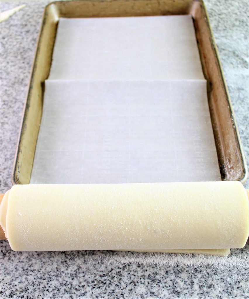 pastry rolled on rolling pin getting ready to unroll on pan