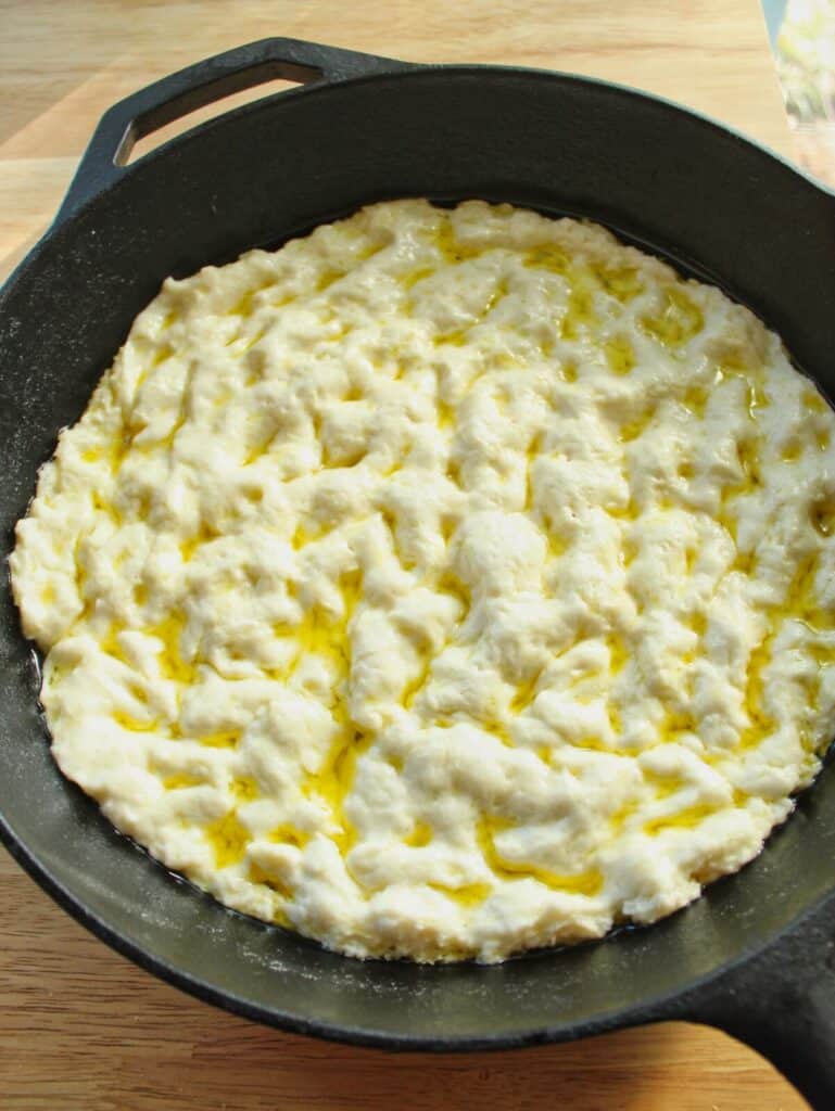 pizza dough dimpled in cast iron skillet.