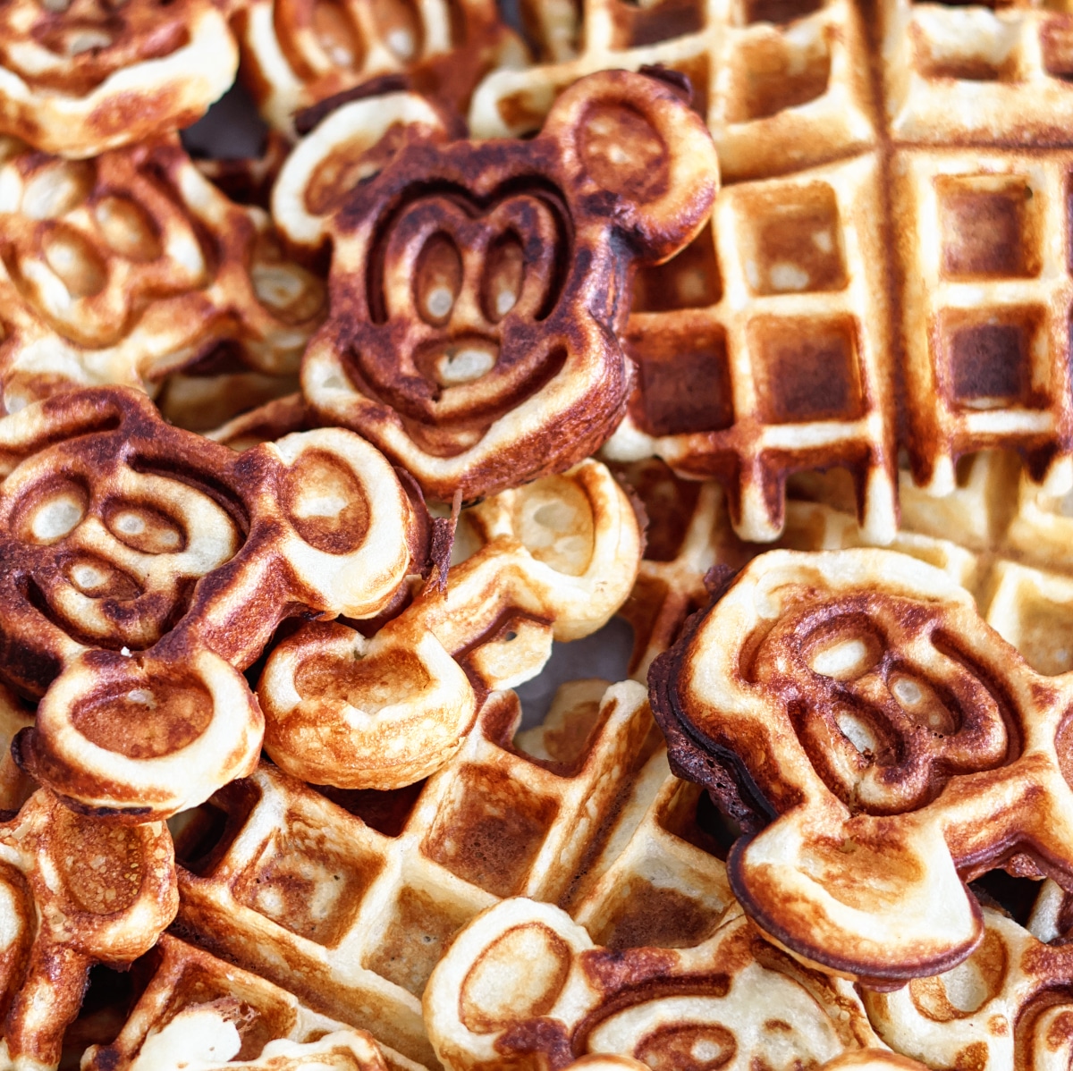 overhead shot of a pile of mickey waffles and regular belgian style waffles.