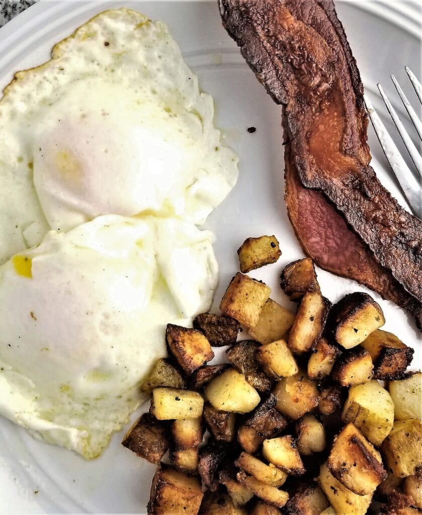 simple breakfast potatoes on a plate with eggs and bacon