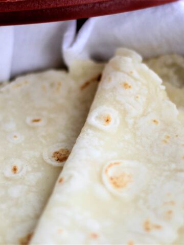 folded over tortillas wrapped in a white flour sack towel