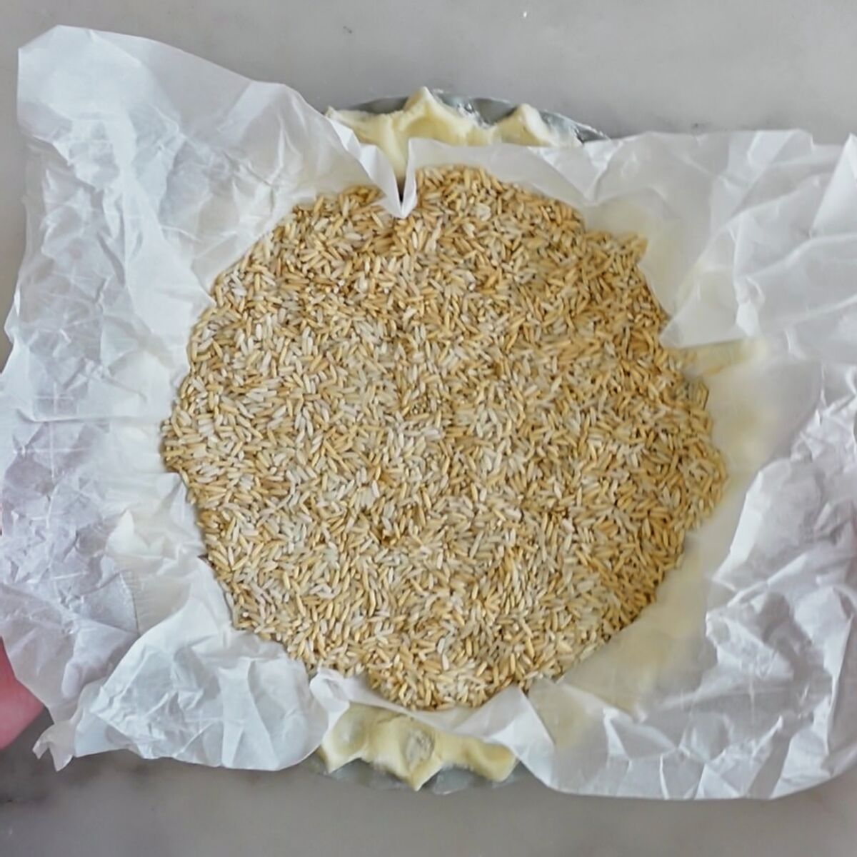 pie crust lined with parchment and filled with rice.