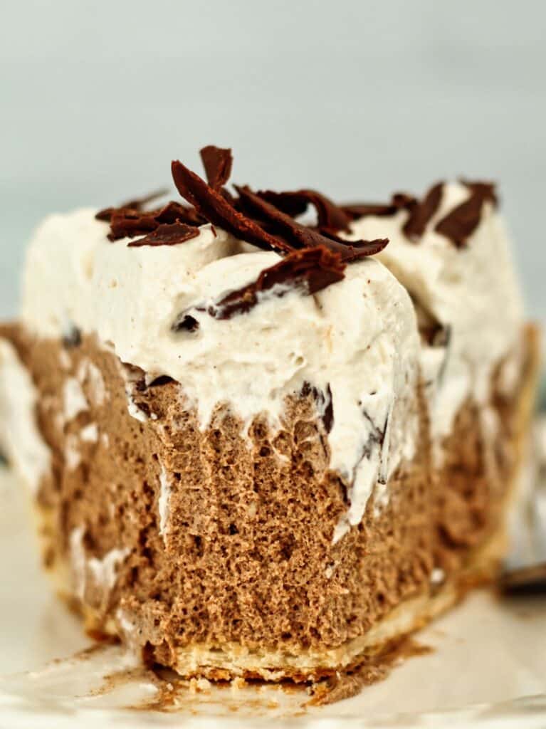 one slice of gluten free french silk pie on white plate with fork marks at tip where one bite was taken.