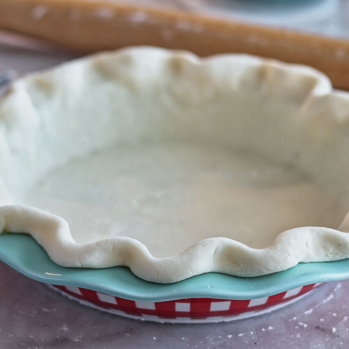 pie crust in blue and red checked pie plate.