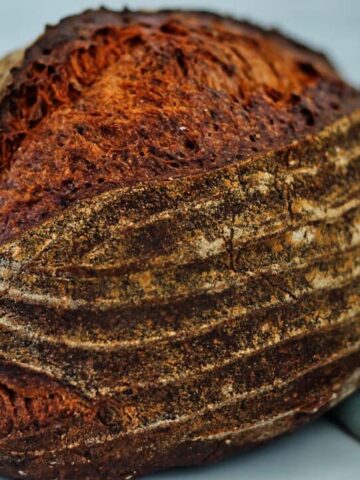 landscape view of gluten free sourdough bread on white countertop with green tea towel.