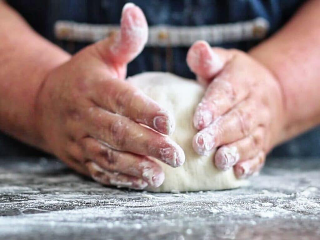 shaping dough into a batard on floured granite counter.