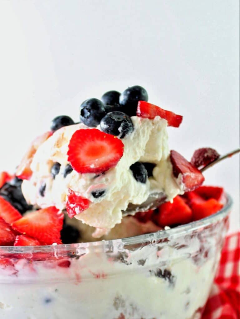 scooping a large scoop of berry trifle out of glass bowl.