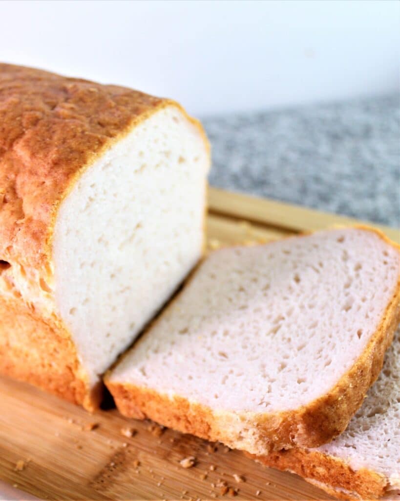 sliced gluten free white sandwich bread on wooden cutting board.