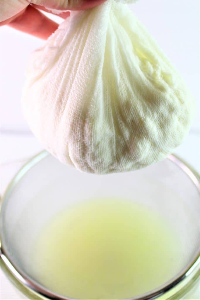 draining ricotta cheese in cheesecloth over sieve and bowl