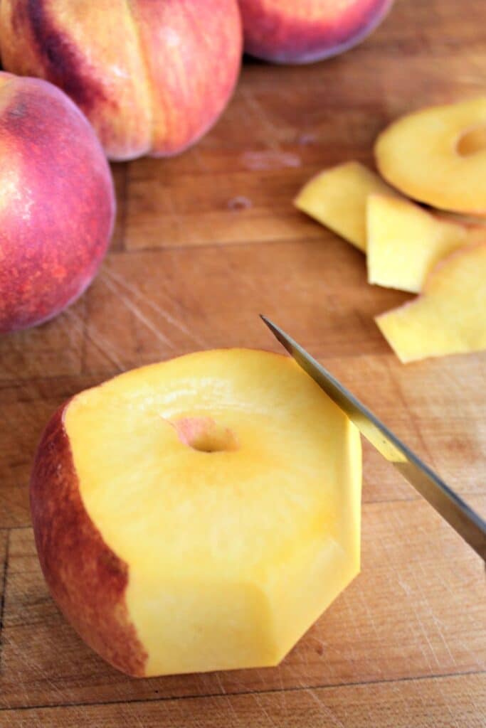 peeling peaches by cutting off the skin with a knife