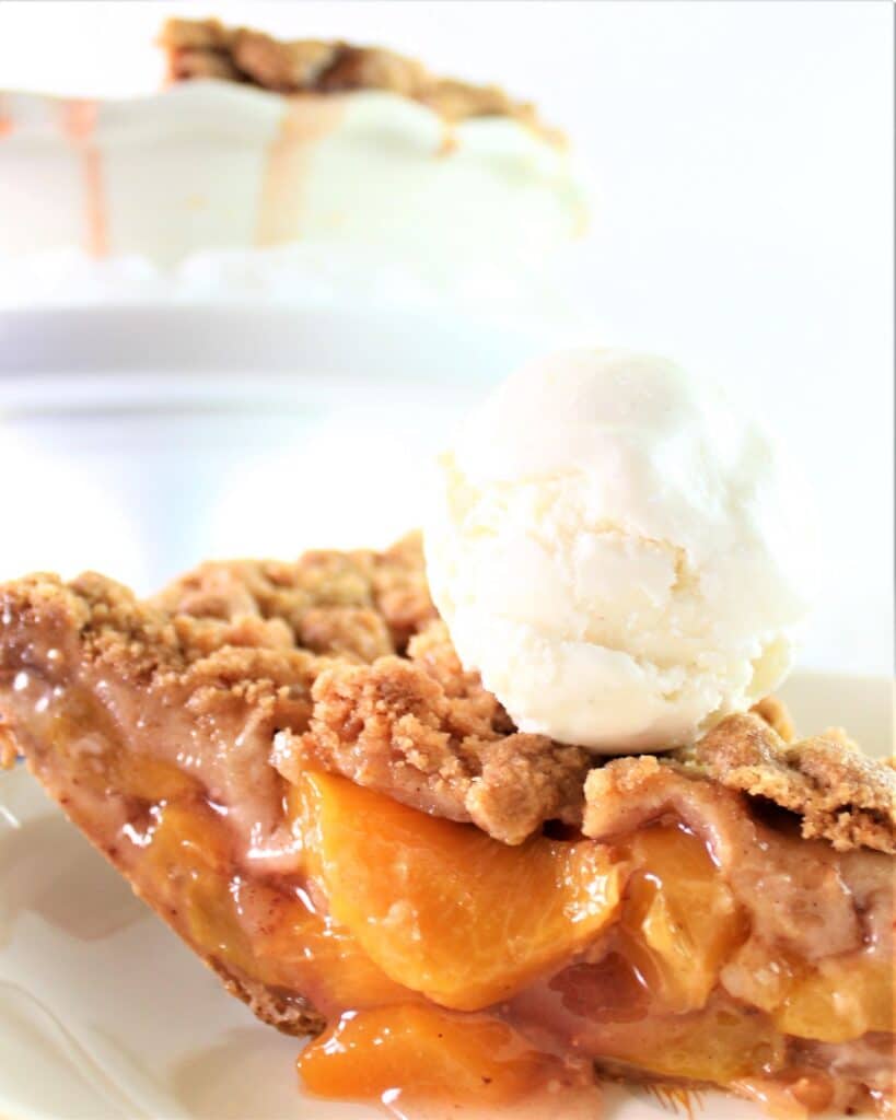 slice of gluten free peach crumb pie with vanilla ice cream scoop