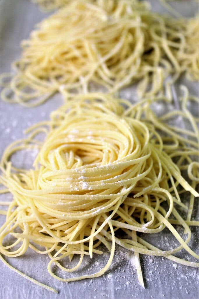 homemade gluten free pasta in individual nests on a sheet tray