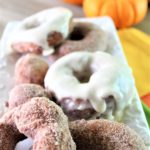 gluten free pumpkin donuts on white tray with pumpkins in the background