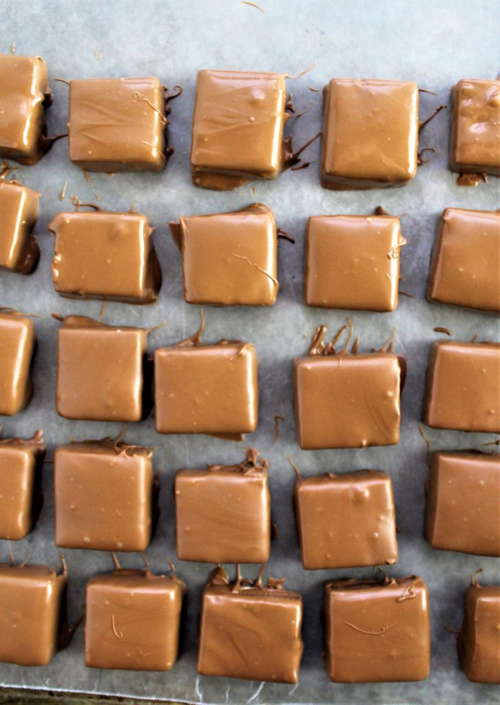 several dipped squares of ganache on waxed paper-lined baking sheet