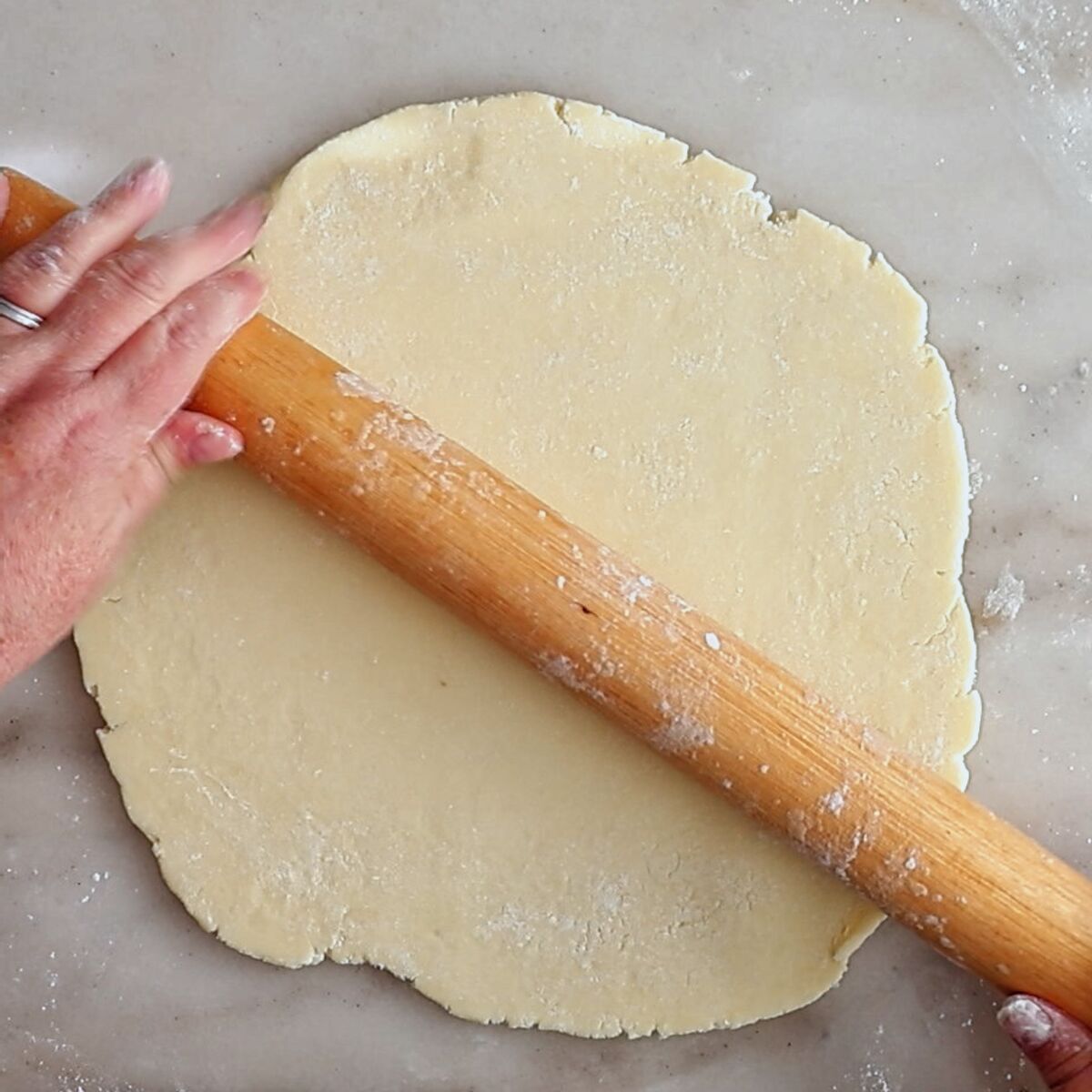 rolling out pie crust on marble surface.