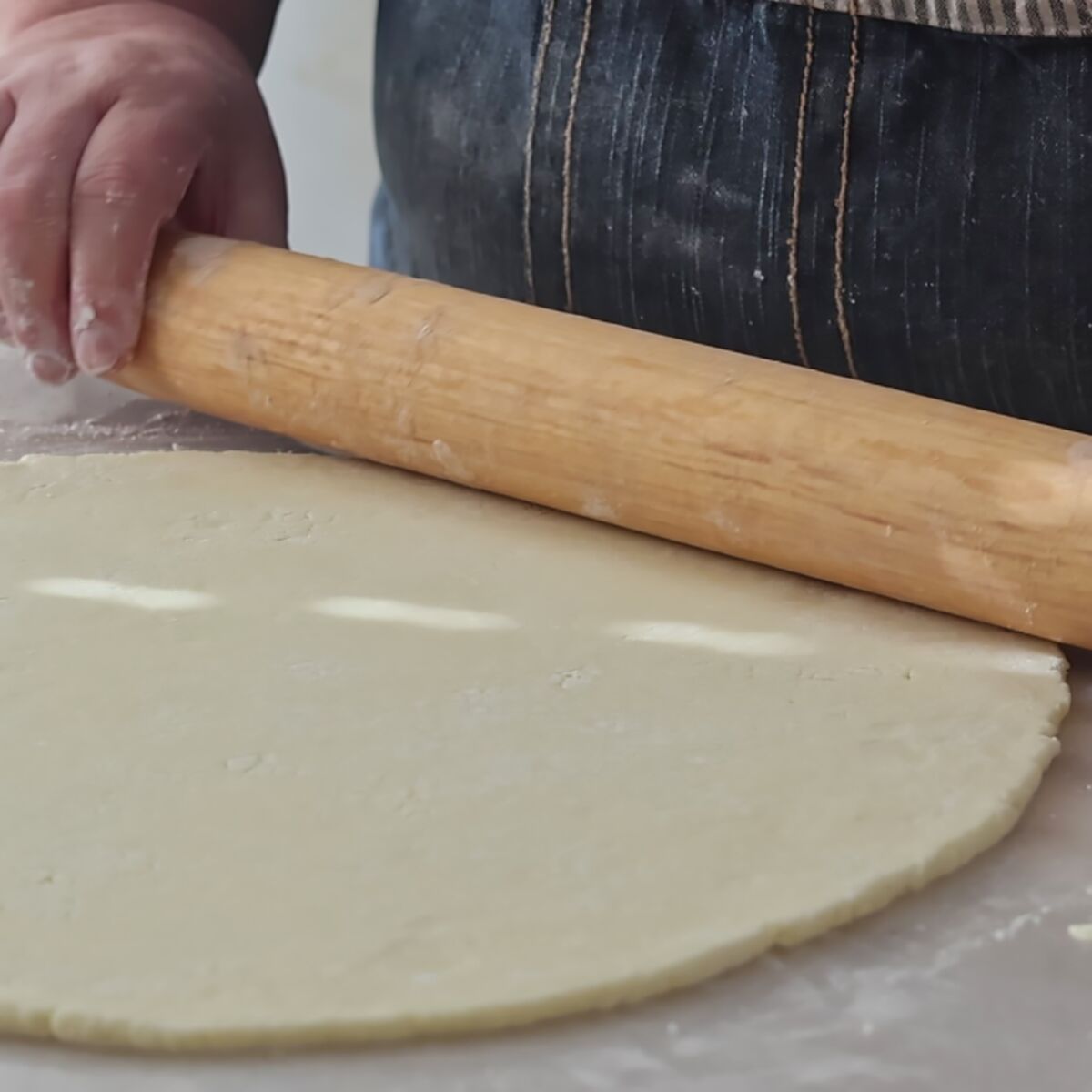 rolling out pie crust with french wooden rolling pin.