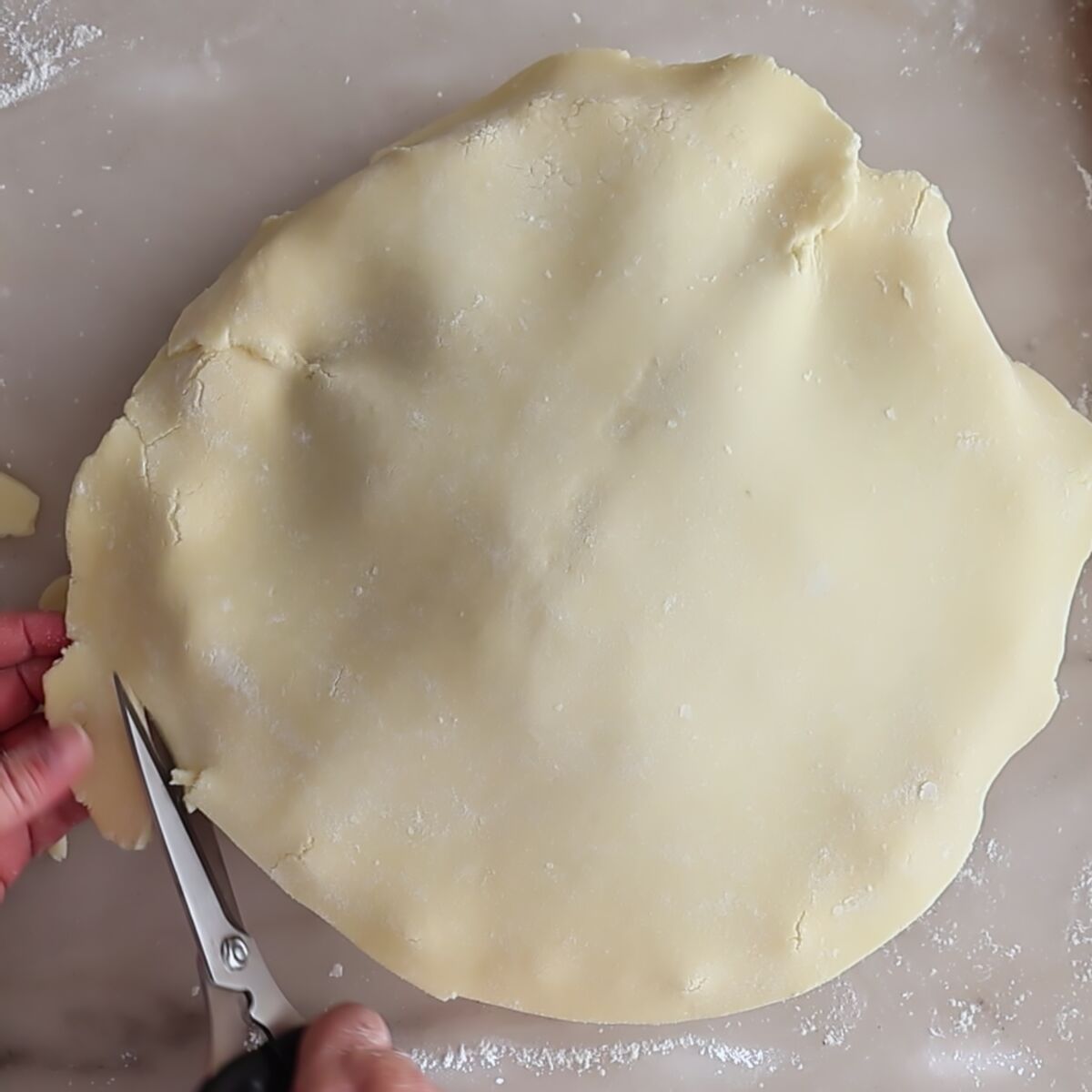 cutting excess pie crust from sides with scissors.