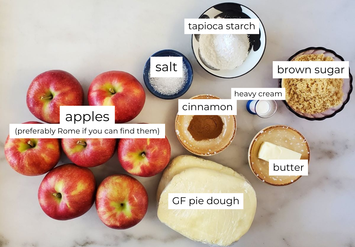 apple pie ingredients measured out and labeled on white marble.