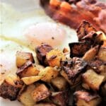 simple breakfast potatoes on white plate with eggs and bacon