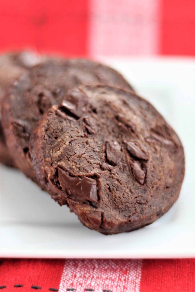 mexican chocolate cookies on white square plate over red checked napkin.
