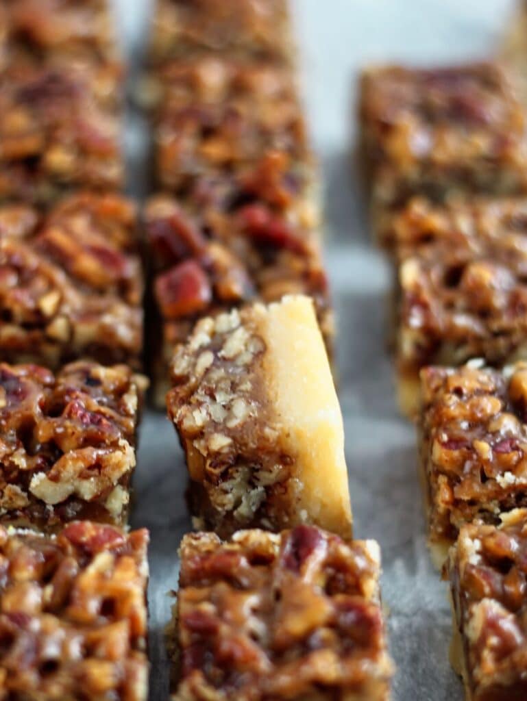 rows of pecan squares on parchment paper with one tipped over on its side.