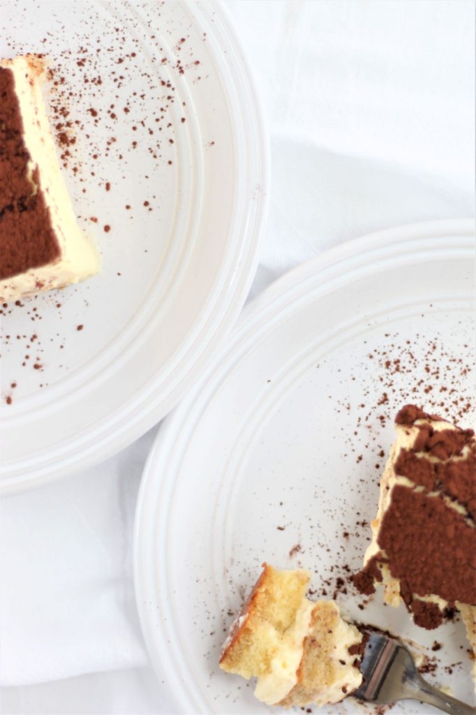 overhead shot of two pieces of tiramisu on white plates