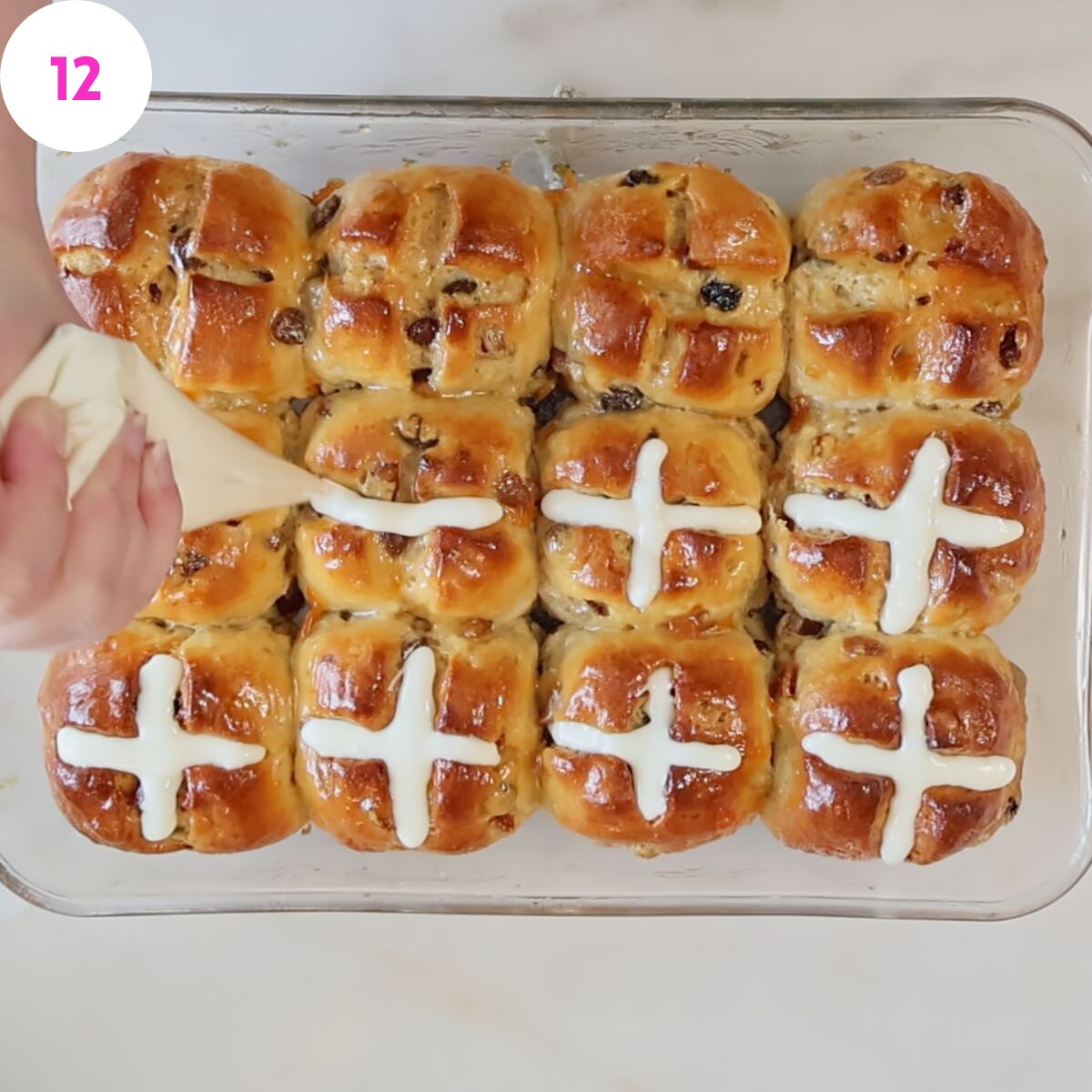 piping cross on top of baked buns.