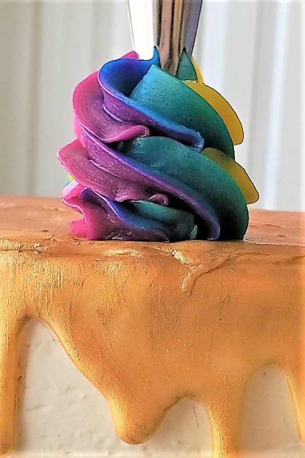 piping rainbow swirl on top of cake